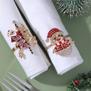 Close-up of golden Santa and Snowman napkin rings with red enamel and rhinestones