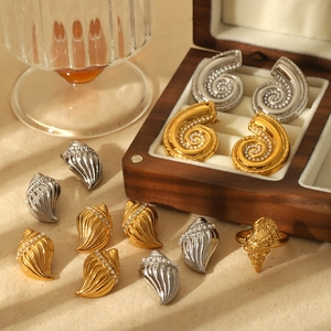 Golden and silver nautilus shell stud earrings and ring set on an elegant wooden jewelry box