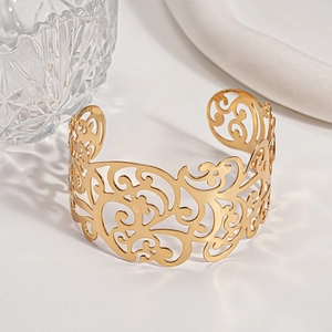 Dettaglio ravvicinato del bracciale rigido dorato bohémien con motivi floreali intagliati