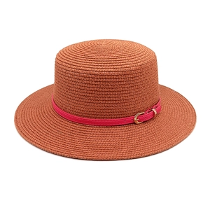 Detail view of woven straw sun hat with pink leather band and gold buckle fastener