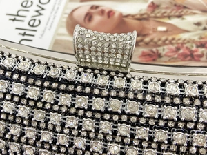 Macro detail of silver clutch buckle with sparkling crystals on premium evening bag