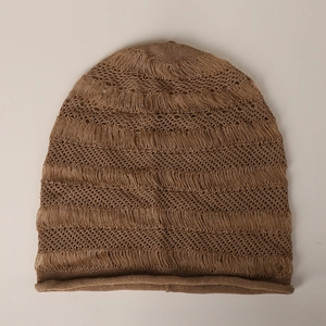Détail d'un bonnet en maille marron avec tissage ajouré et finitions à franges rétro