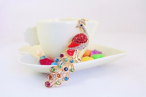 Detail of peacock keychain featuring vibrant red crystals and gold-plated alloy base