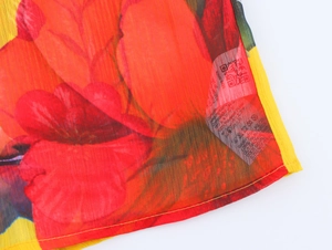 Macro detail of floral print chiffon fabric with delicate yellow stitched hem finish