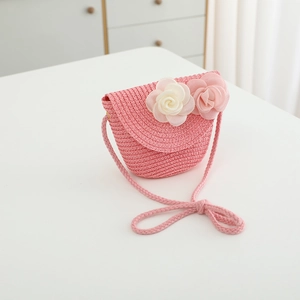 Detailed view of pink straw crossbody bag with decorative large fabric flowers for girls