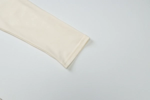 Macro shot of double-needle stitching on off-white knit sleeve cuffs with fine fabric texture