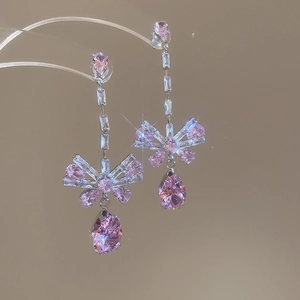 Detail of elegant silver bow earrings featuring sparkling pink pear-shaped zircon drops