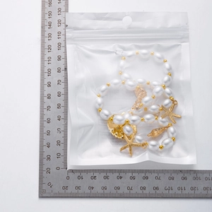 Size measurement of golden pearl starfish and shell necklace in clear packaging