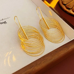 Detailed view of layered gold circular earrings with textured finish in a wooden display box