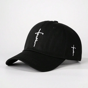 Close-up detail of white faith cross embroidery on black cotton baseball cap fabric