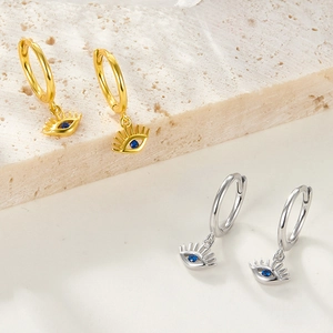 Detailed view of gold and silver devil's eye hoop earrings with blue stones