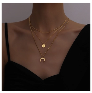 Detailed view of layered gold necklace set with sun and moon pendants on a model