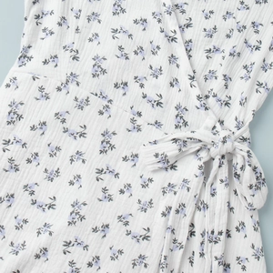Close-up of cotton floral wrap dress featuring seersucker texture and waist tie detail