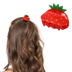 Macro detail of red acrylic strawberry hair claw clip showing glossy finish and green leaf