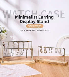 Detail of minimalist earring display stand with golden metal racks and wooden base