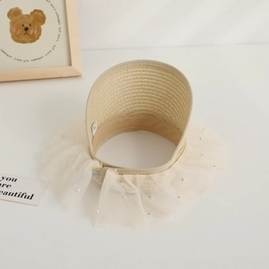 Close-up of a cream woven sun hat featuring lace ruffles, pearls, and a wide straw brim