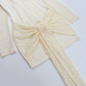 Detailaufnahme des cremefarbenen Spitzenkleides mit großer Schleife und Blumenmustern