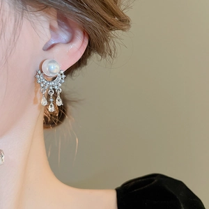 Detail of luxury pearl and rhinestone tassel earrings shown on model for elegant style