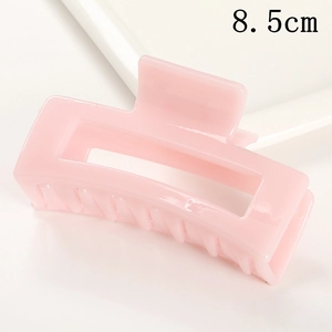 Detail view of a 8.5cm pink rectangle hair claw clip on a white ceramic tray
