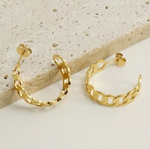 Detail of 18k gold plated Cuban link hoop earrings on a minimalist stone background