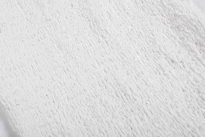Gros plan du tissu texturé blanc montrant le motif seersucker et les détails plissés
