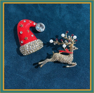Detailed view of crystal-encrusted Christmas hat and reindeer brooches with red accents