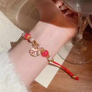 Détail du bracelet tressé rouge avec des perles en cristal et un pendentif poney coloré
