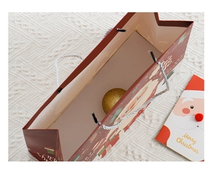 Detail of red Christmas gift bag with Santa Claus, matching card and golden ornament