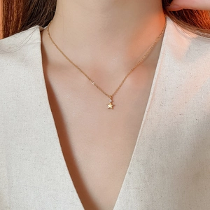 Dettaglio della collana con ciondolo a stella dorata e zircone sulla clavicola