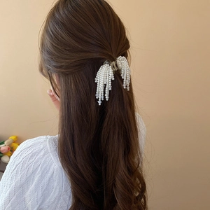 Detail of elegant faux pearl tassel hair claw clip worn in a stylish half-up hairstyle