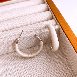Gros plan de boucles d'oreilles en C en cuir crème sur un plateau de bijoux en bois