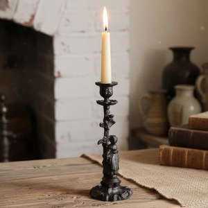 Bougeoir vintage en fonte avec relief de fille et bougie conique sur table en bois