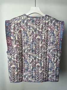 Detailed vertical quilting and vintage floral pattern on this blue sleeveless puffer vest