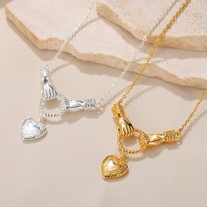 Detailed close-up of 18K gold heart pendant necklaces on textured stone surface