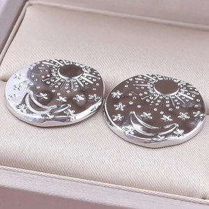 Detailed macro view of 304 stainless steel earrings featuring sun and moon relief patterns