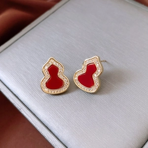 Macro shot of gold-plated gourd stud earrings with red enamel and pavé-set zircons