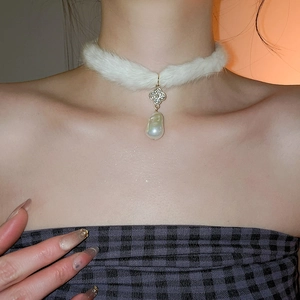 Detail of white faux fur choker featuring a sparkling clover charm and baroque pearl drop