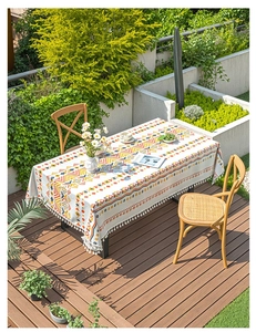 Detail of bohemian geometric tablecloth with decorative white tassels on an outdoor patio