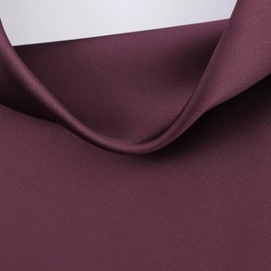 Vista macro del tessuto in raso viola scuro con un elegante drappeggio e consistenza lucida