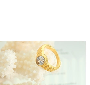 Detailed view of a textured gold-plated ring featuring a clear round gemstone inlay