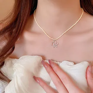 Collana di perline giallo pallido con ciondolo a fiore in zircone indossata da donna