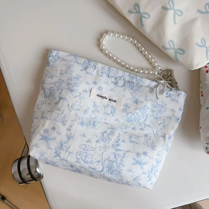 Detail of floral rabbit cotton pouch featuring pearl wrist strap and silver bow charm