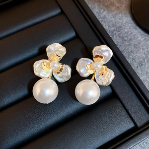 Detailed close-up of petal flower pearl earrings on a premium black leather display tray