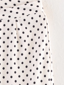 Détail du pantalon blanc à taille haute avec motif à pois noirs classiques sur le tissu