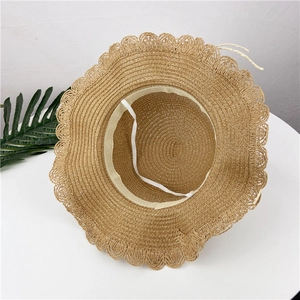 Close-up of woven straw hat featuring a wavy lace edge and white elastic windproof strap