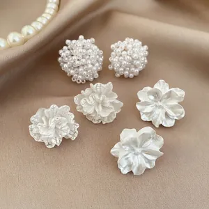 Dettaglio di un elegante set di orecchini a fiore e perle bianche, set di 3 paia.