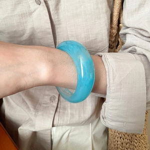 Blue marble resin wide bangle worn by a model in a summer vacation style outfit