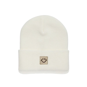 Detailed close-up of cream knit beanie featuring a minimalist square smiley face patch