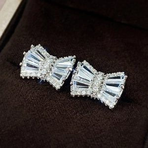 Macro shot of silver bow earrings with clear cubic zirconia in a brown velvet box