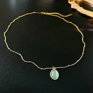 Oval pendant necklace in gold stainless steel with a green cat-eye gemstone